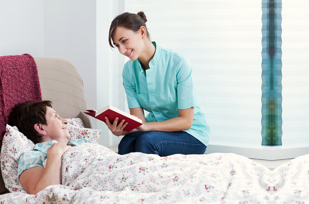 staff reading a book to her patient